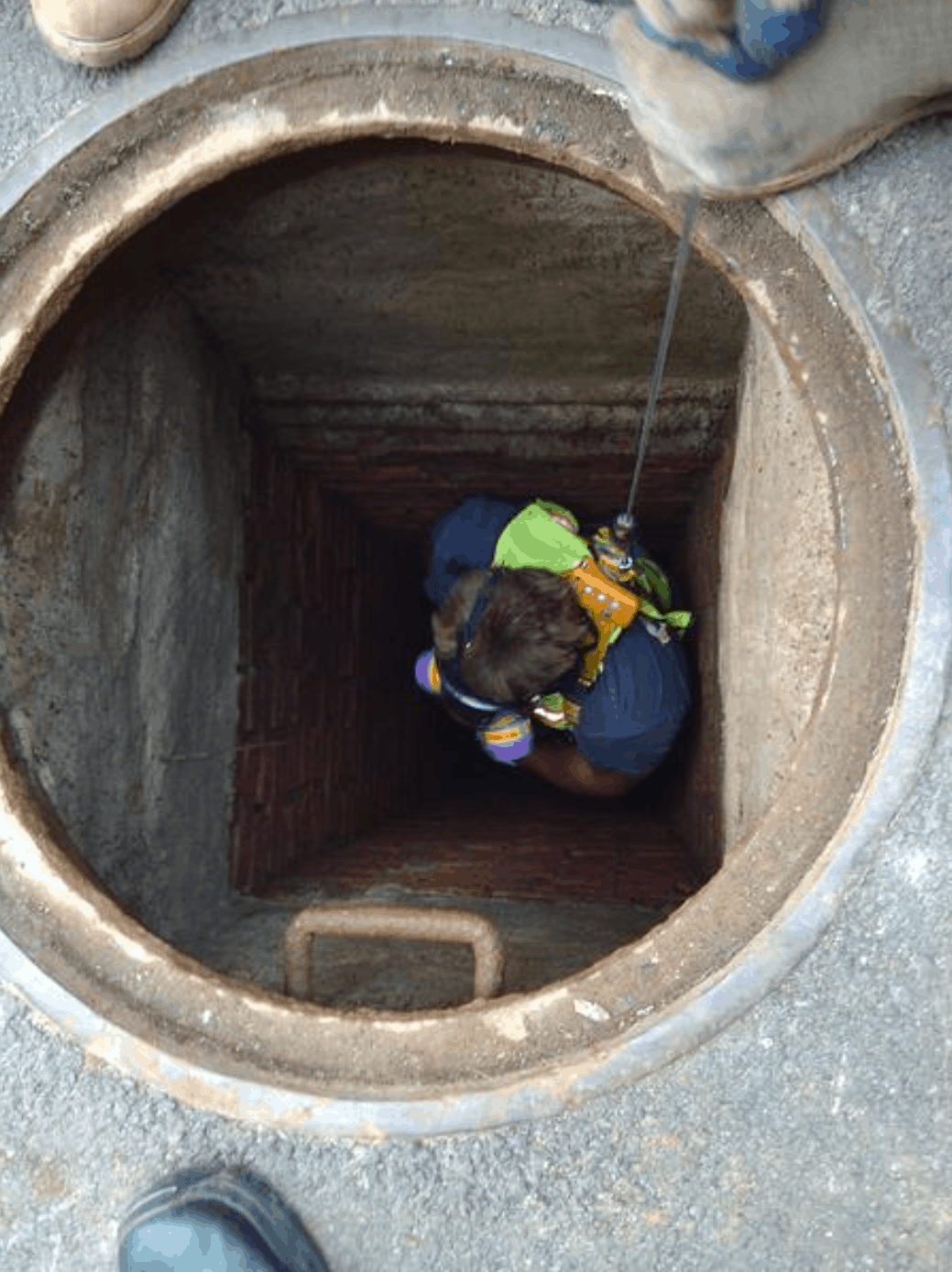 technician from long island sewer and water main being lowered into sewer.