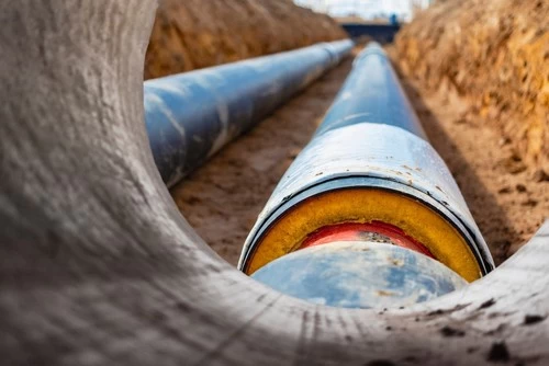 Plumbing pipes laid in a trench and being covered with soil during underground installation