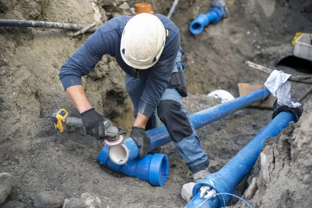 Construction workers laying underground pipes for water, sewerage, electrical lines, and fiber optic cables
