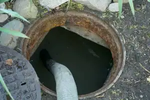 Worker pumping a septic tank or cesspool from a backyard tank located in a rural countryside setting in Long Island, NY