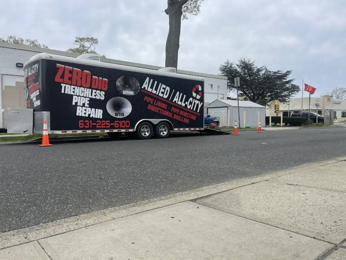 Trenchless pipe repair trailer parked on a street in Nassau County, NY, equipped with specialized tools and equipment for underground pipe repair without digging.